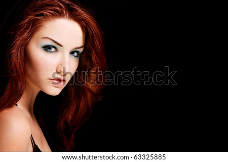 A beauty shot of a young blue eyed woman with her red hair looking at the camera.