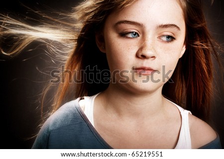 A beautiful young girl with her hair blowing in the wind.