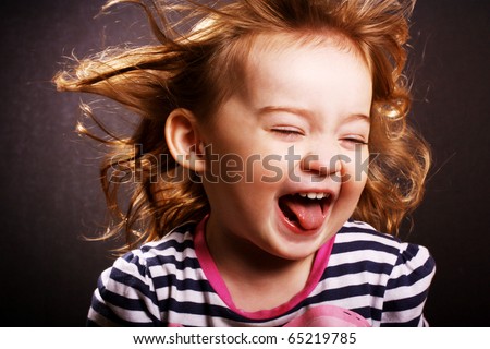 An adorable little girl laughing with wind in her hair.