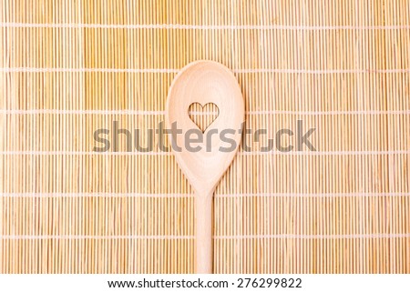 Wooden spoons with heart motif on bamboo serving backgrounds. Wooden kitchen spoon.