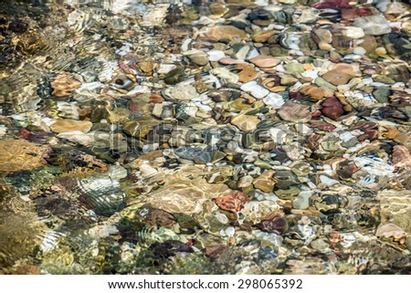 Colored stones under the water, surface reflections. Water Surface.