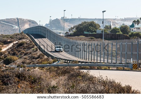 San Diego, California and Tijuana, Mexico international border wall with border patrol vehicle.