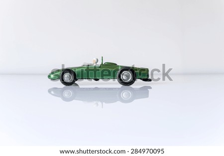 Old toy car plastic green, front view, white background with reflexes, natural light