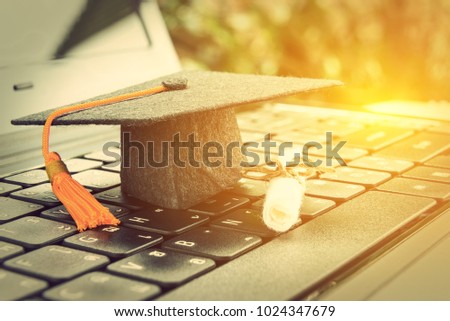 online learning or e-learning and online graduate certificate program concept : Black graduation cap, diploma on a laptop computer keyboard, depicts distant learning can be done via cyber / internet
