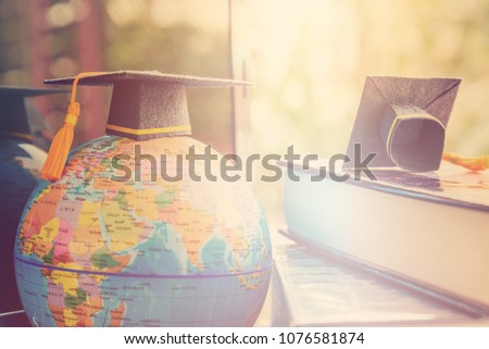 Graduate study abroad program concept : Black graduation cap on a globe map and books, depicts knowledge can be learned online anywhere and everywhere, even in universities or campus around the world.