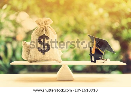 Money cost saving for goal and success in school, education concept : US dollar bills / cash in hessian bags, a black graduation cap or hat, a certificate / diploma and a book on simple balance scale.
