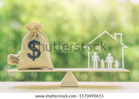 Cost of living, home loan, family finance and child trust fund concept : US dollar bags, family members live inside a house on basic balance scale, depicts the expenditure a family should prepare for