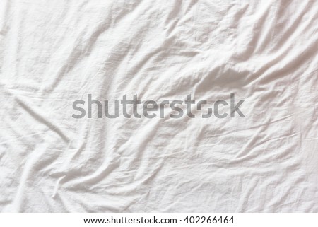 Top view of wrinkles on an untidy white bed sheet in a bedroom after a long night sleep and waking up in the morning. A pattern can be used for making a wavy flag by distort / displacement map method.