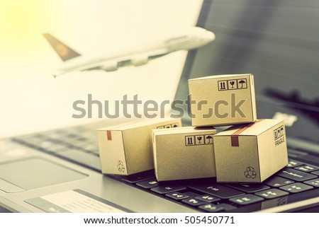 Mini cardboard boxes on a laptop with a plane flies behind. For several purposes or ideas about transportation, international freight, global shipping, overseas trade, regional  / local forwarding.