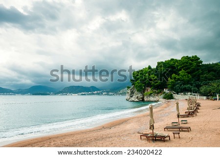 luxury beach resort with sunbeds and umbrellas with rainy sky / beach resort with rainy sky