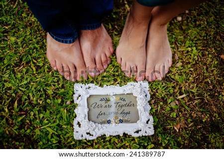 couple's feet together on green grass close up