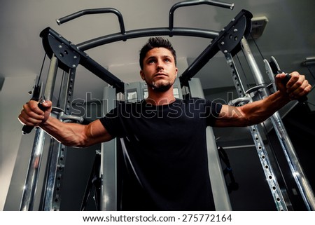 handsome bodybuilder works out  pushing up excercise in gym on trainer in black t shirt