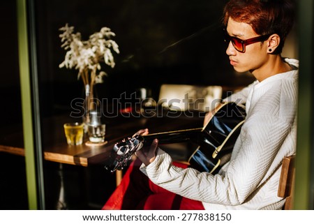 asian handsome artist play acoustic guitar in cafe