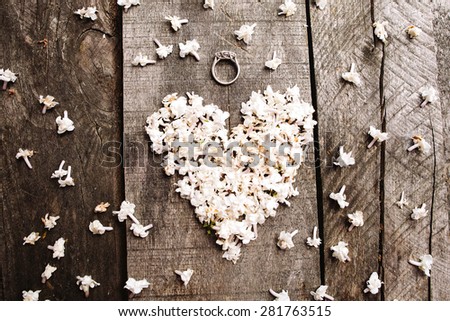 gentle beautiful white heart shape lilac flowers with proposal wedding ring on vintage wood table