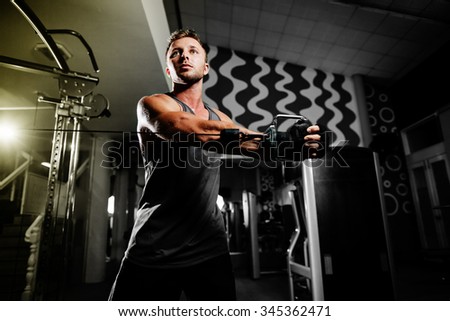 handsome bodybuilder motivated works out  pushing up excercise in gym on black background