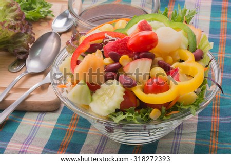 Vegetable salad with oriental salad dressing on stripe table cloth.