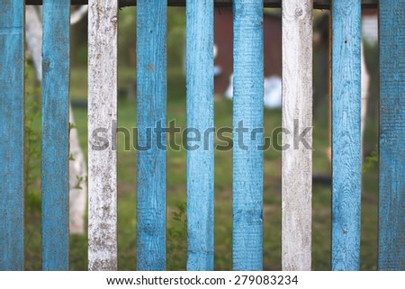 White and blue rustic wooden fence. Natural countryside look with out of focus background behind fence