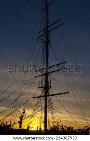 Ship with a big tall sail in silhouette on sunset standing on the Hamburg dock, Germany
