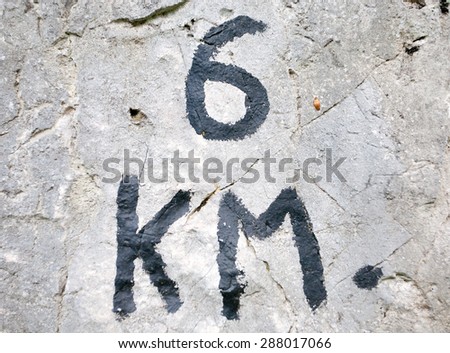 Indication of distance written on stones with black paint, signal along trekking path