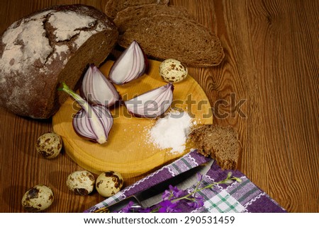 bread black head of garlic and onion halves knife and fork on wooden table