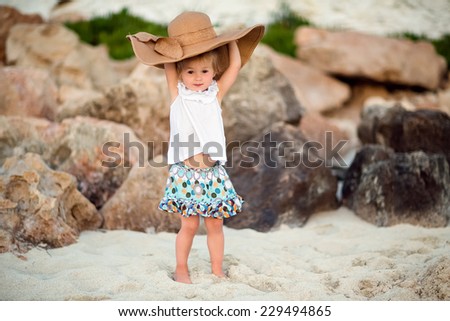 Very cute girl holding a hat in the background of stones