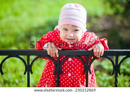 portrait of a young smiling girl in a red coat with polka dots