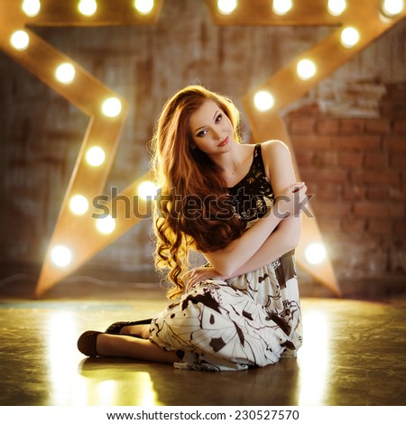 Portrait of a very cute girl with red hair in a black and white dress against the background lights