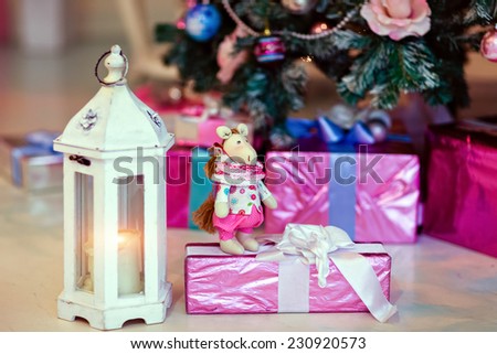 Soft toy horse on a background of Christmas gifts next to the lantern