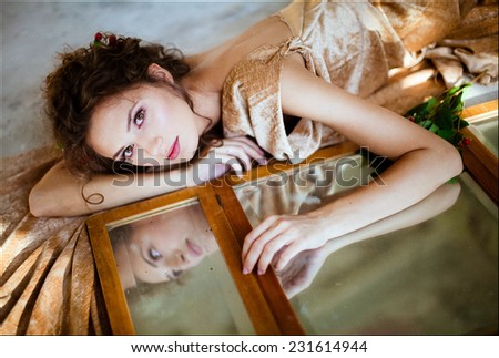 sensual brunette girl lies on a mirror, reflecting in it