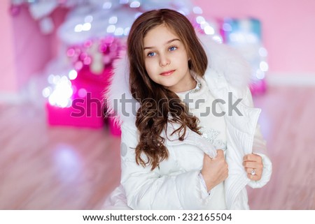Very cute long-haired young girl with blue eyes in a white coat sitting on the floor