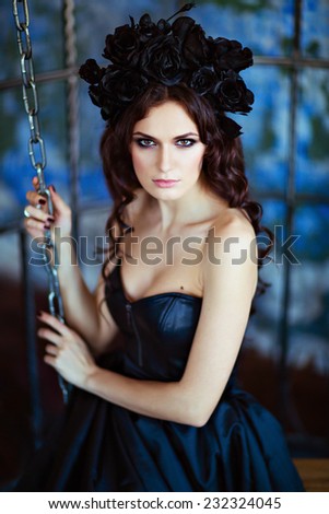 Curly brunette with a wreath of black flowers sits amid circuits