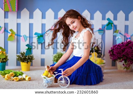 Cute long-haired young girl in a blue skirt sitting on the floor and plays with Chicks for Easter