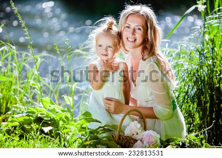 Mom and daughter happy smile on the background of the forest and water in backlight