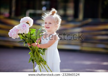 Charming blonde girl with peonies in the hands of