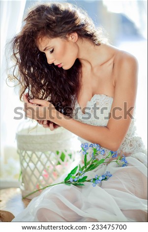 portrait of sensual curly haired girl in a white dress with closed eyes in profile against the window