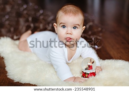 Very cute baby lying on the floor on the background of Christmas lights and displays language