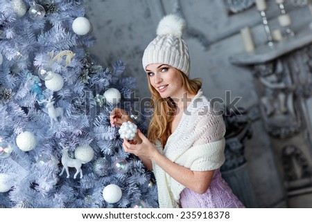 Very beautiful girl with blue eyes in a white hat costs about silver Christmas tree