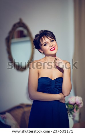 Beautiful brunette girl in a blue dress smiling in interiors