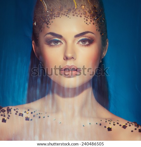 Portrait of a glamorous very beautiful girl brunette with sequins on the face in the Studio