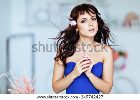 Portrait of a gentle sensual young girl brunette in blue dress with flowing hair