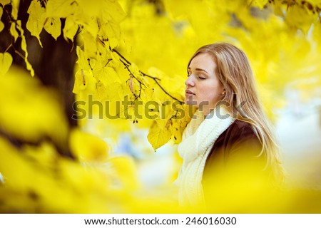 Very beautiful redhead girl with freckles with my eyes closed on a background of yellow autumn leaves