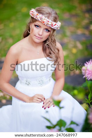 Portrait of a beautiful bride with a diadem of flowers on his head and in a white dress against the background of the autumn asters
