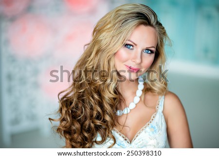 Portrait of a very beautiful sexy sensual girl with gorgeous curly blonde hair, blue eyes, close-up