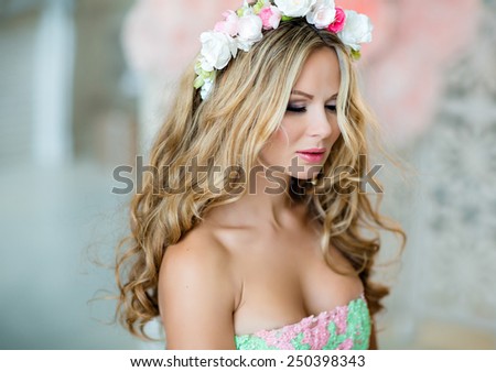 Very beautiful sensual girl with curly blond hair and a wreath of delicate spring flowers, close up with my eyes closed