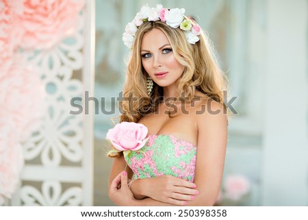 Very beautiful blonde girl in a lace dress with a wreath of flowers on his head, against the spring pink flowers, close up