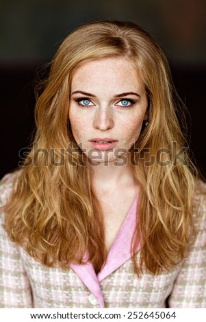 Portrait of sensual very beautiful redheaded girl with freckles in pink tweed suit, a close up of the front