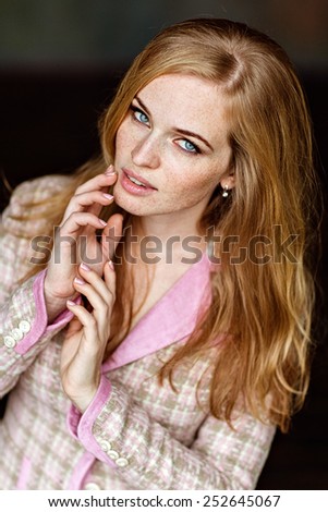 Portrait of sensual very beautiful redheaded girl with freckles in pink tweed suit, close up