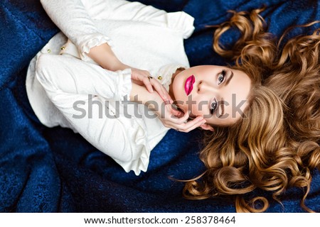 Portrait of a very beautiful sensual glamorous red-haired girl in a white blouse and a blue skirt lying on the floor in the Studio on a dark background