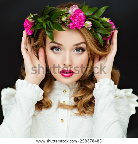 Portrait of a beautiful sensual glamorous yellow-haired girl in a white blouse with a wreath of flowers on his head, in the Studio on a dark background, close up