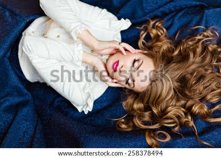 Portrait of a very beautiful sensual glamorous red-haired girl in a white blouse and a blue skirt lying on the floor in the Studio on a dark background with your eyes closed